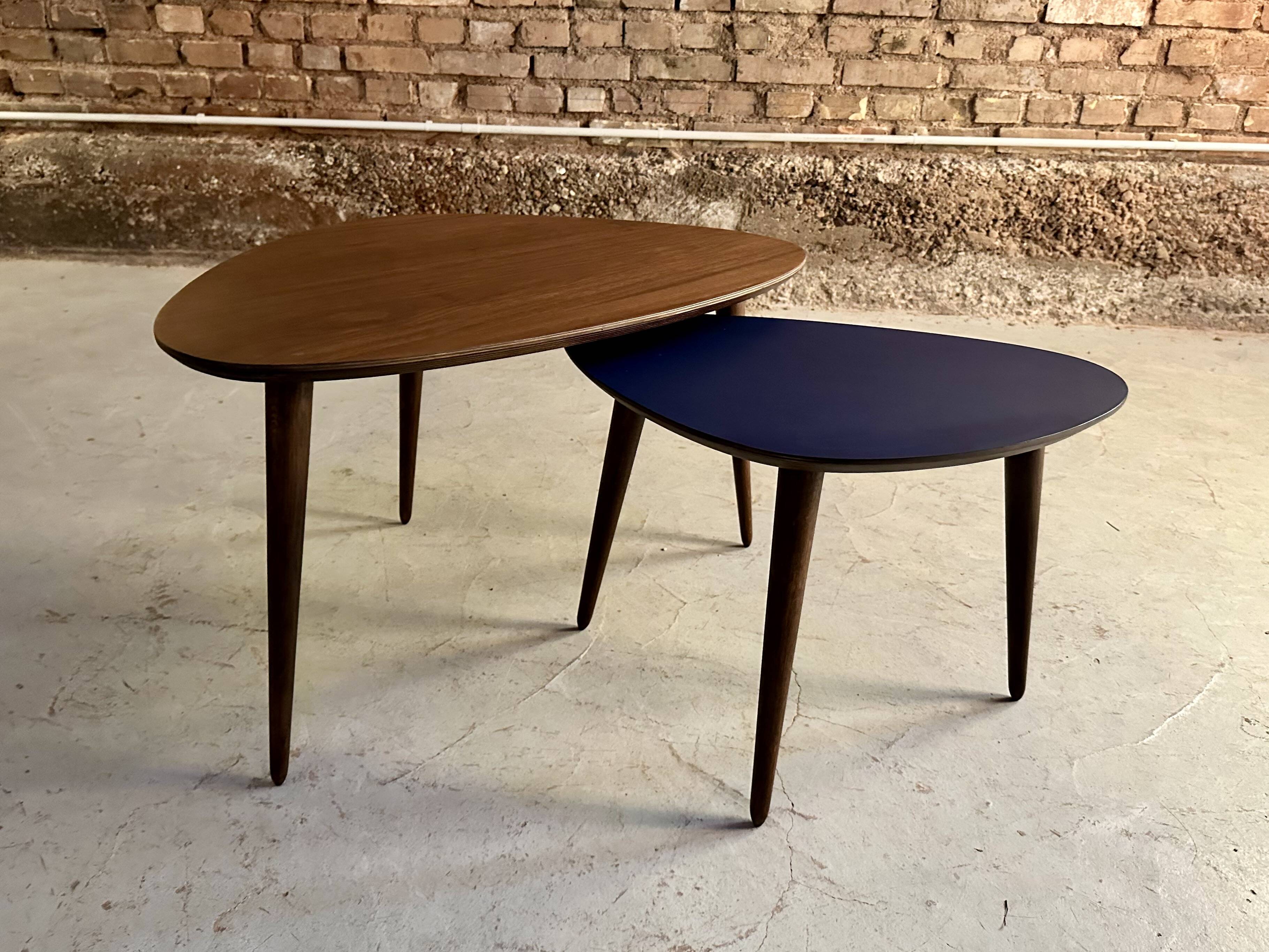 A pair of tripod and nesting coffee tables in walnut and midnight blue.