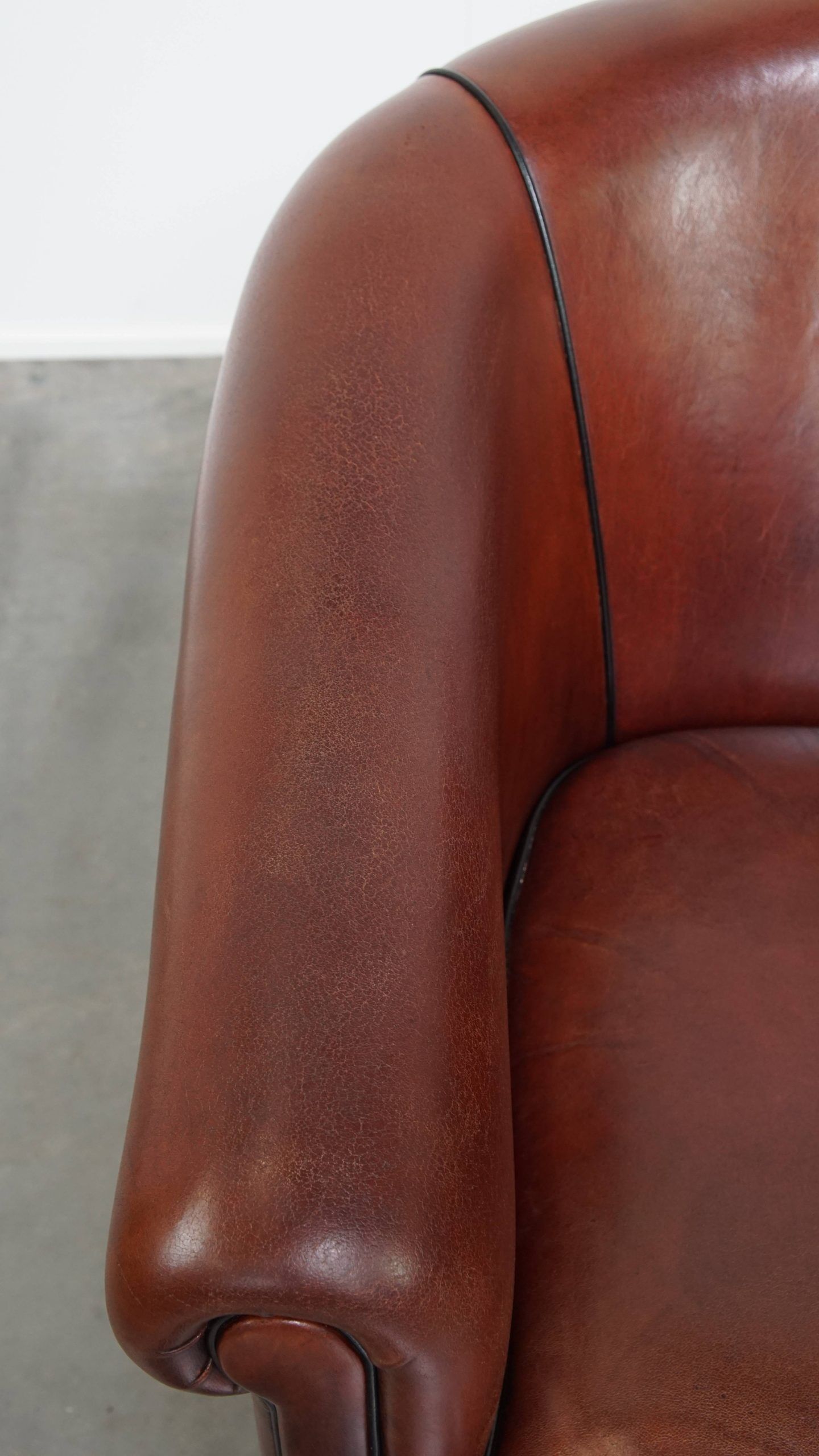 Sheepskin club armchair in a warm deep colour finished with black piping