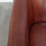 Sheepskin club armchair in a warm deep colour finished with black piping