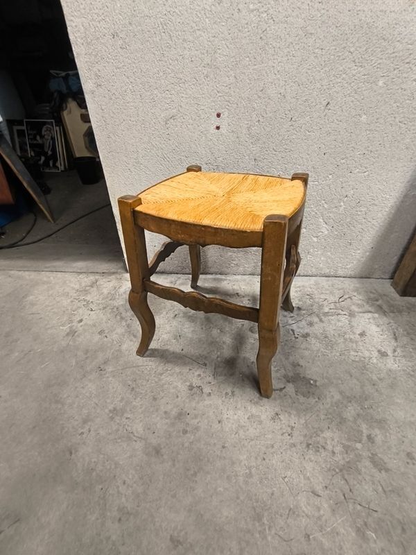 Rustic wooden stool with a straw seat.