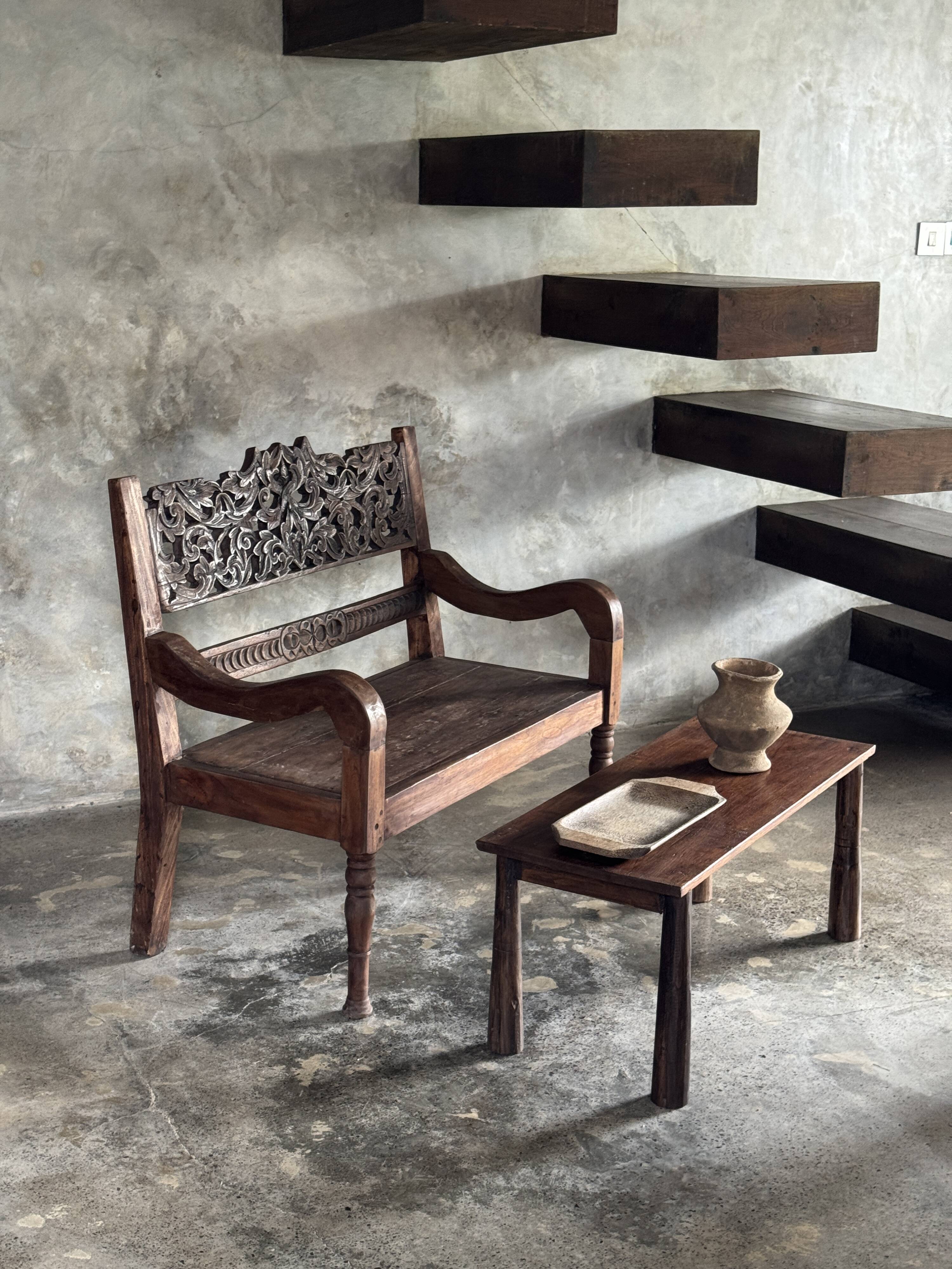 Small antique Indonesian bench in carved teak with plant and floral motifs.