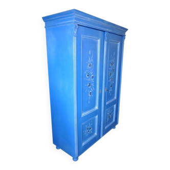 Medium blue painted wooden double wardrobe with hand-painted floral patterns on the doors.