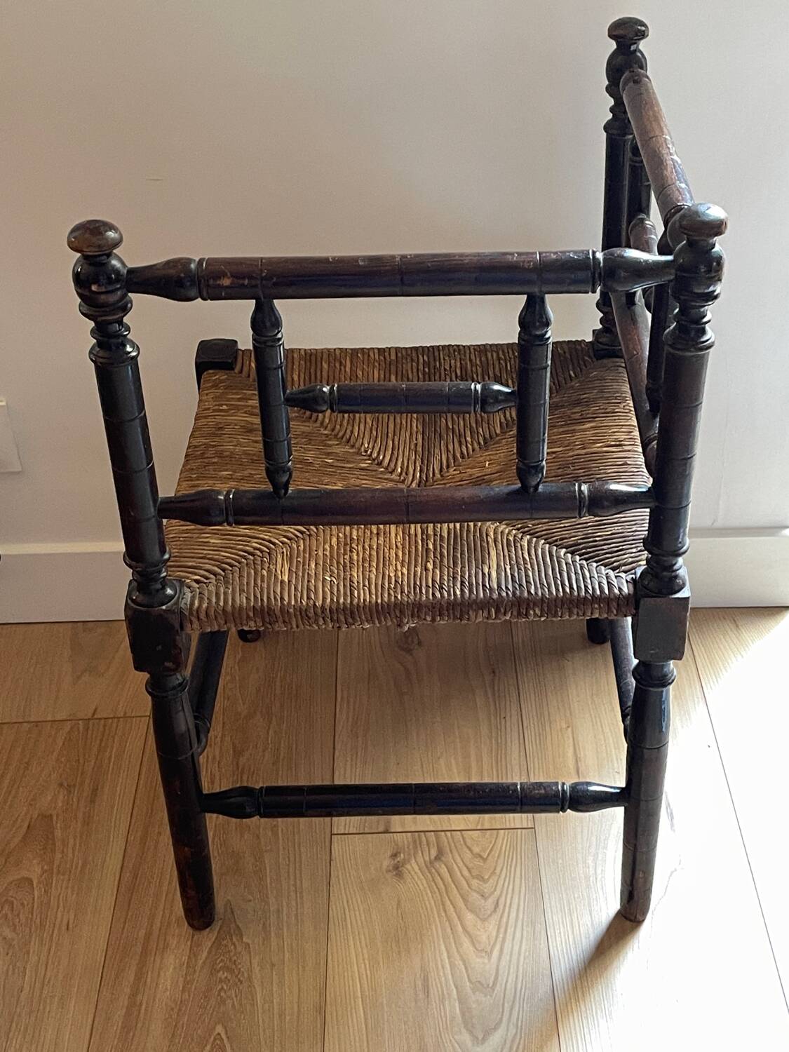 Corner chair made of turned wood with a straw seat.