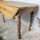 Antique wooden drop-leaf table with turned legs.