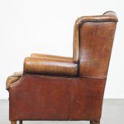 Cognac-colored sheep leather wingback chair finished with black piping
