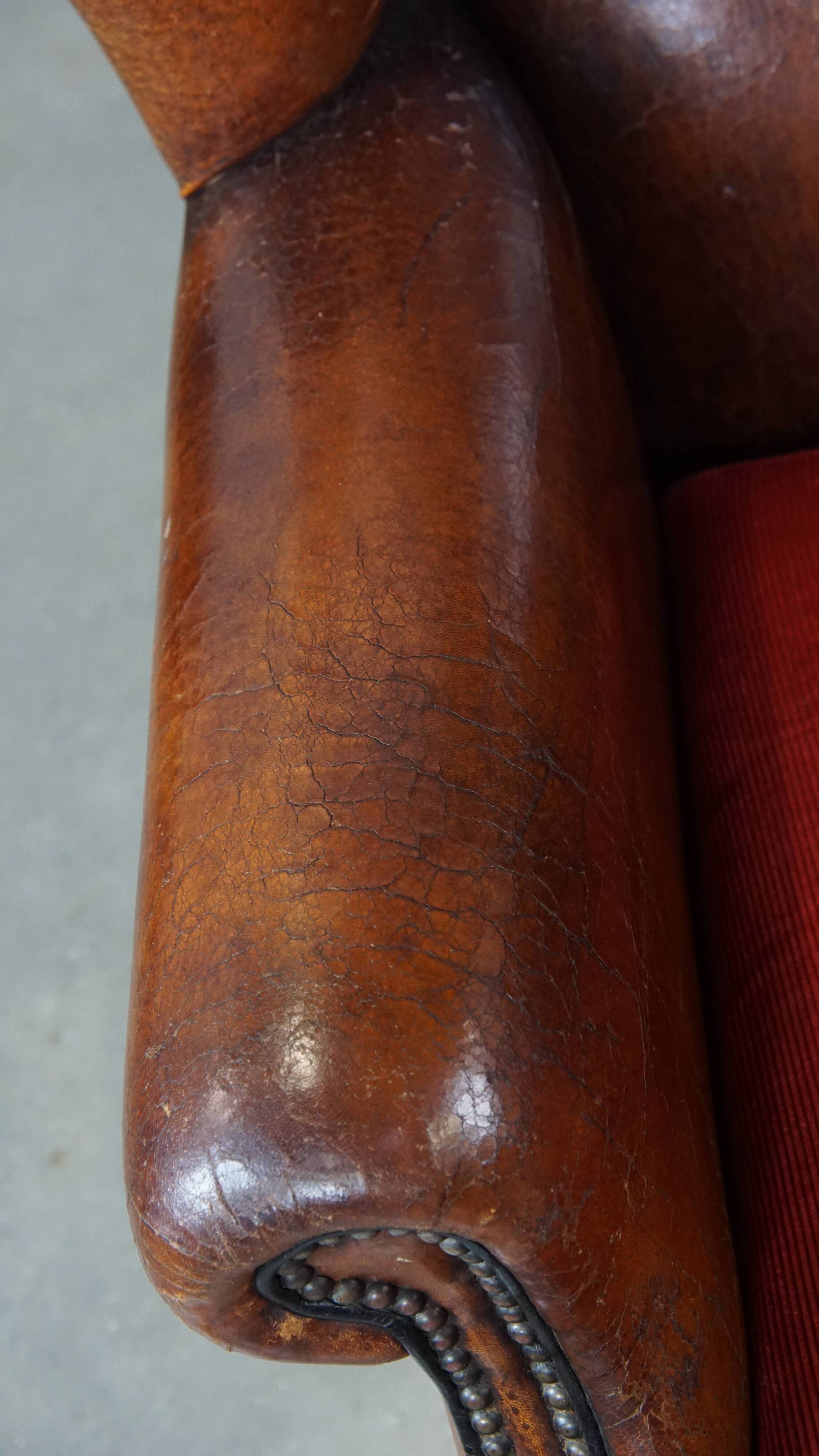 Sheepskin leather wingback chair with a red corduroy seat cushion