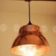 Industrial pendant lamp in the shape of a hammered copper bell.