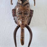 A large Senufo mask made of colored wood, decorated with an anthropomorphic figure