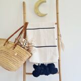 Handwoven throw with black stripes and pom-poms