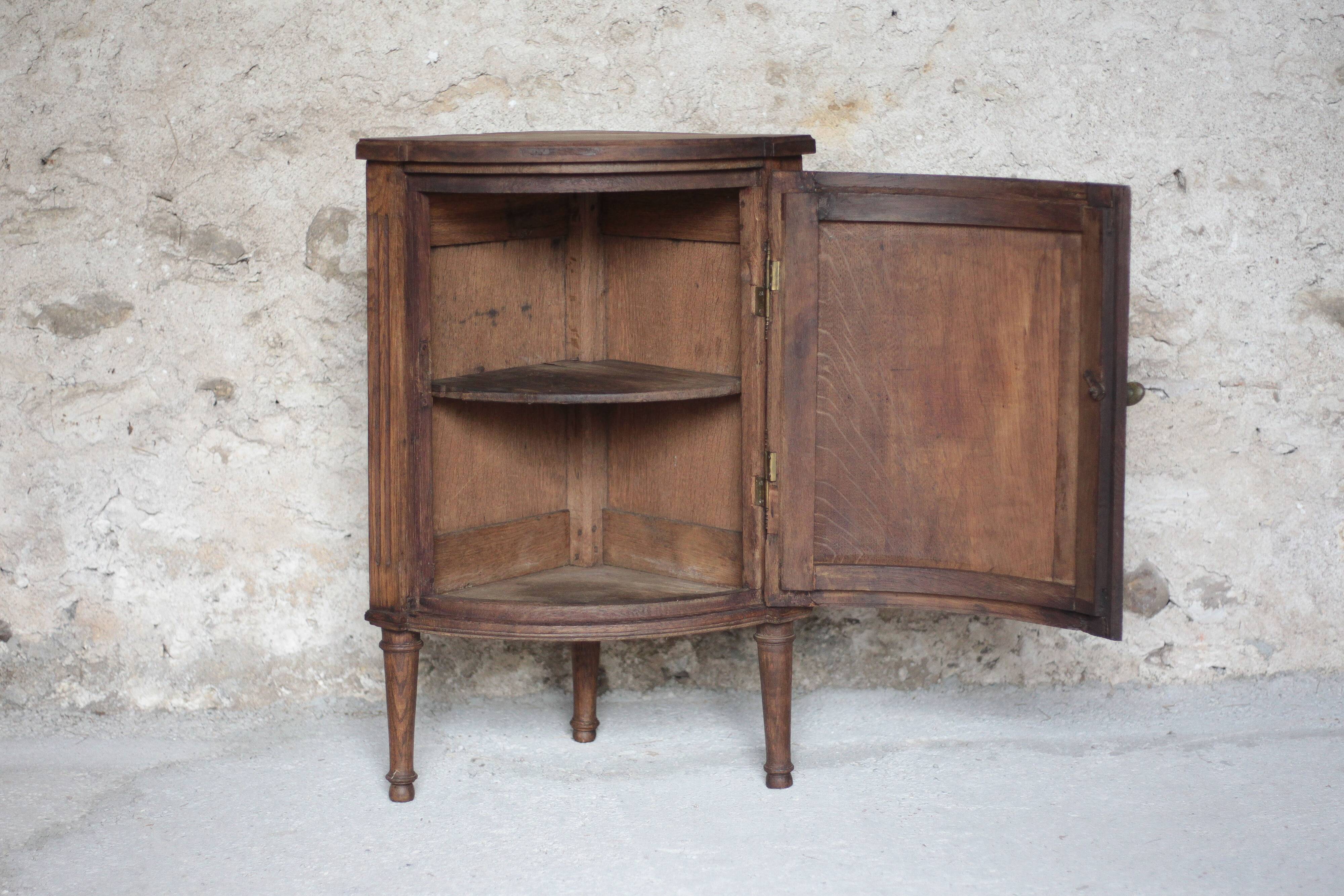 Antique wooden corner cabinet with a curved door.