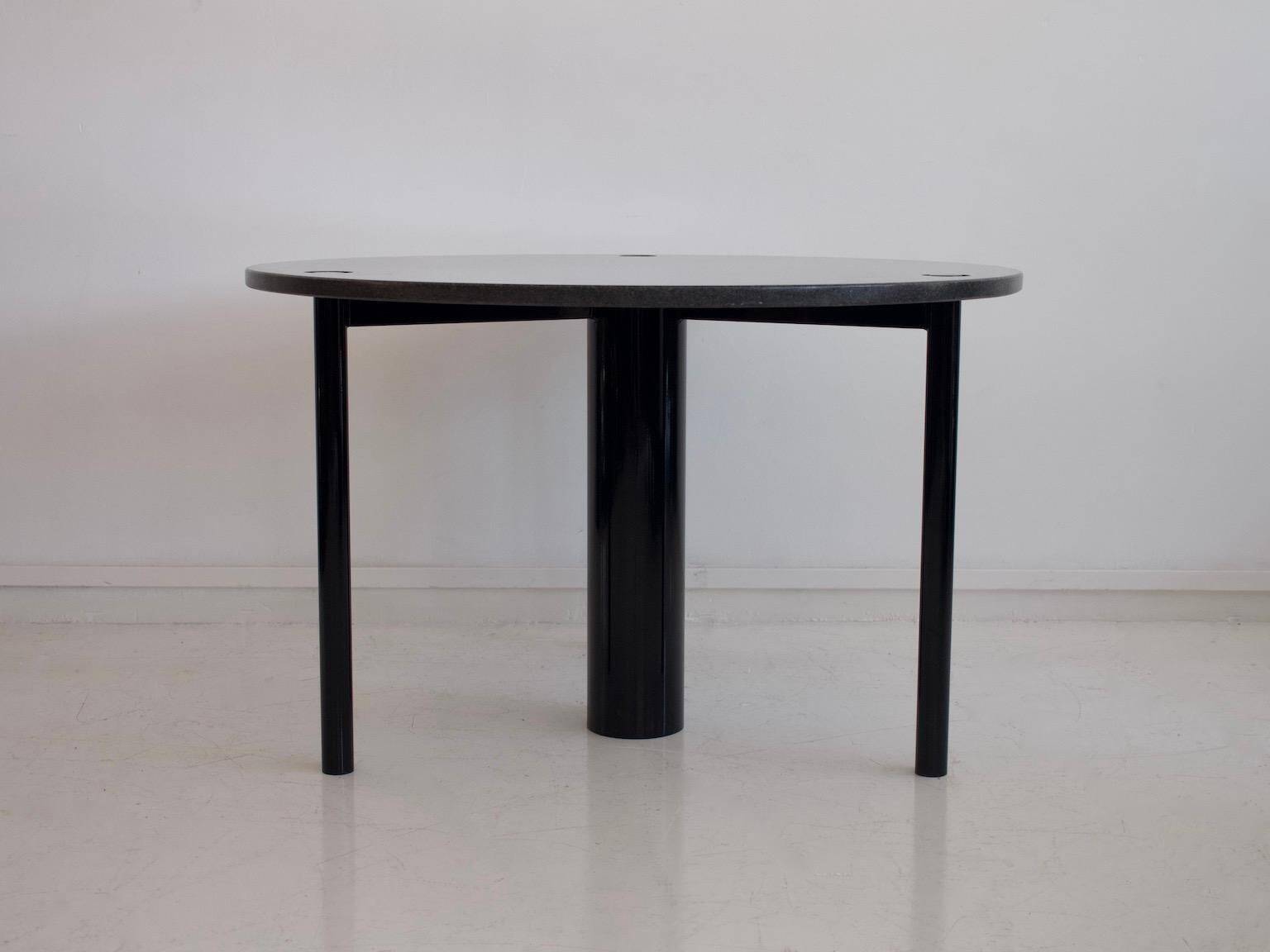 Round dining table in black lacquered metal with a granite top.