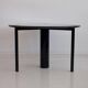 Round dining table in black lacquered metal with a granite top.