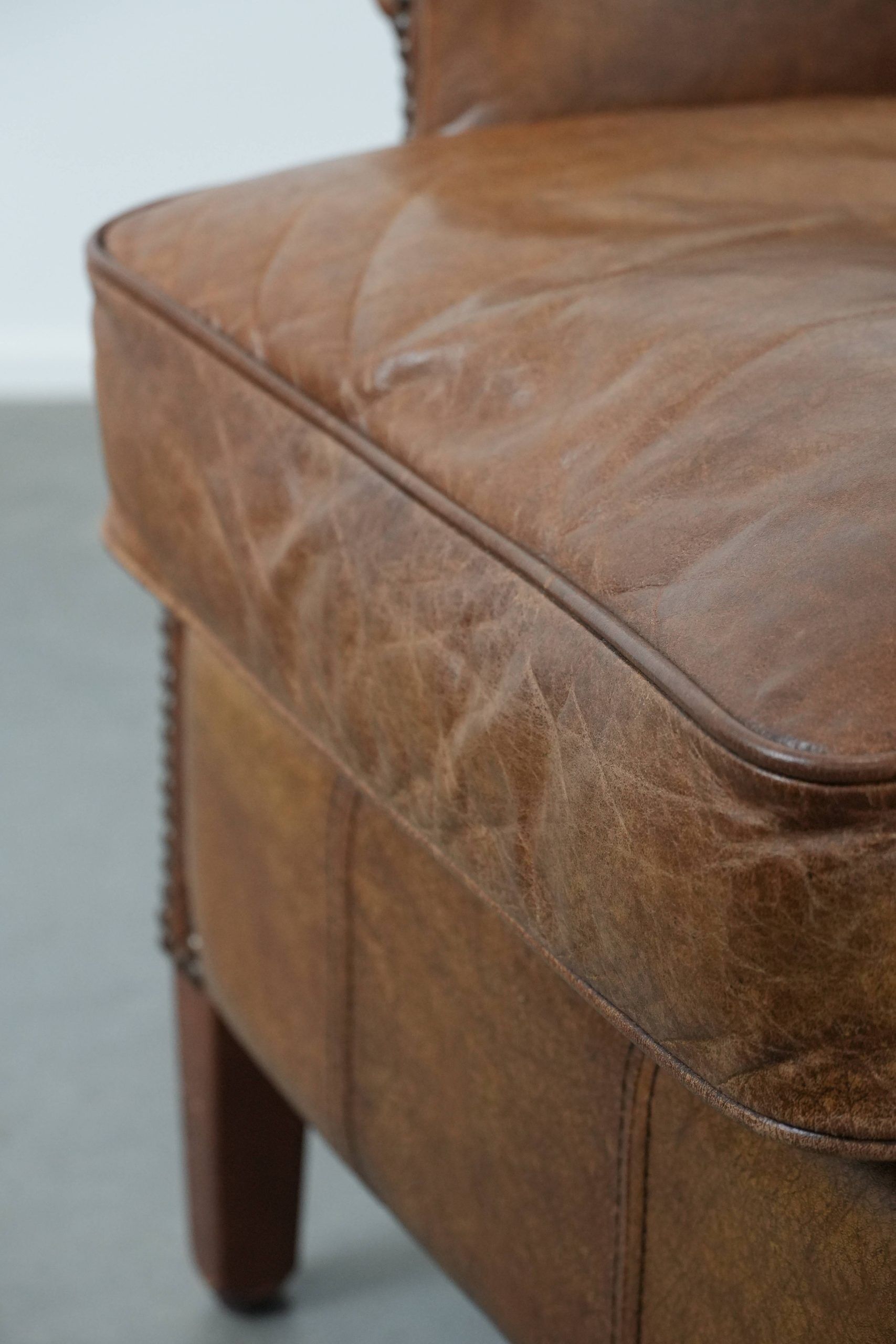 Cognac-coloured wingback armchair in English style made of cowhide leather