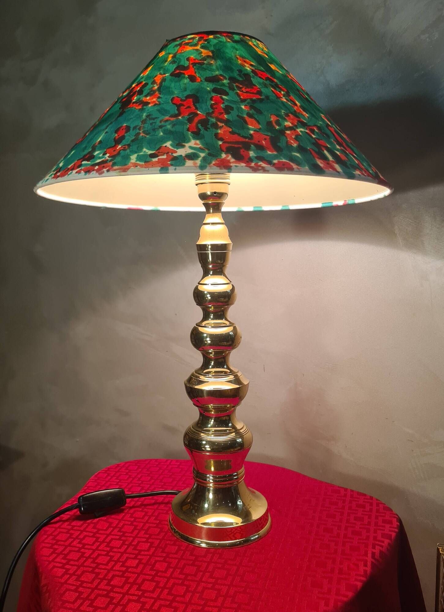 This elegant table lamp features a sculptural base in shiny gold brass.