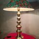 This elegant table lamp features a sculptural base in shiny gold brass.