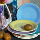 Seven pastel-colored plates mixed with vintage earthenware