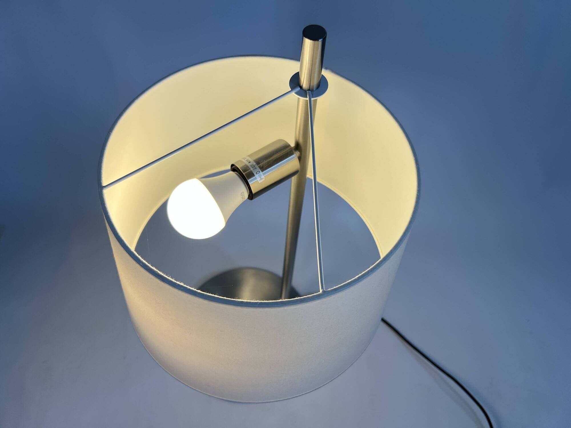Large brushed metal table lamp with an ecru shade.