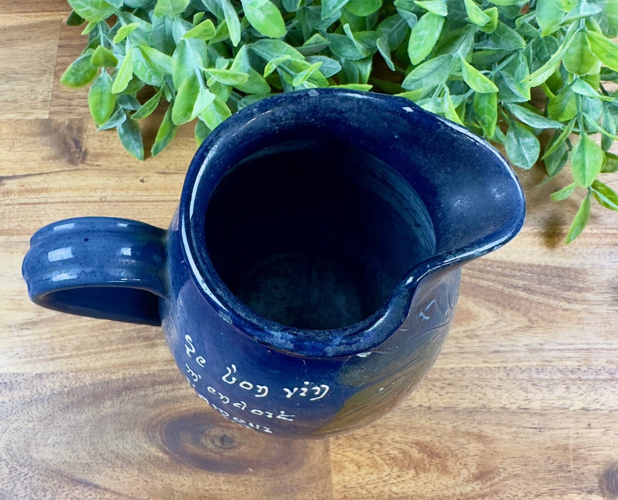 Blue ceramic pitcher with vintage artisan inscription decoration.