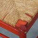 Vintage 1970s red wooden chair with a woven wicker seat