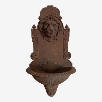 Old cast iron wall fountain with lion's head