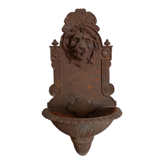 Old cast iron wall fountain with lion's head