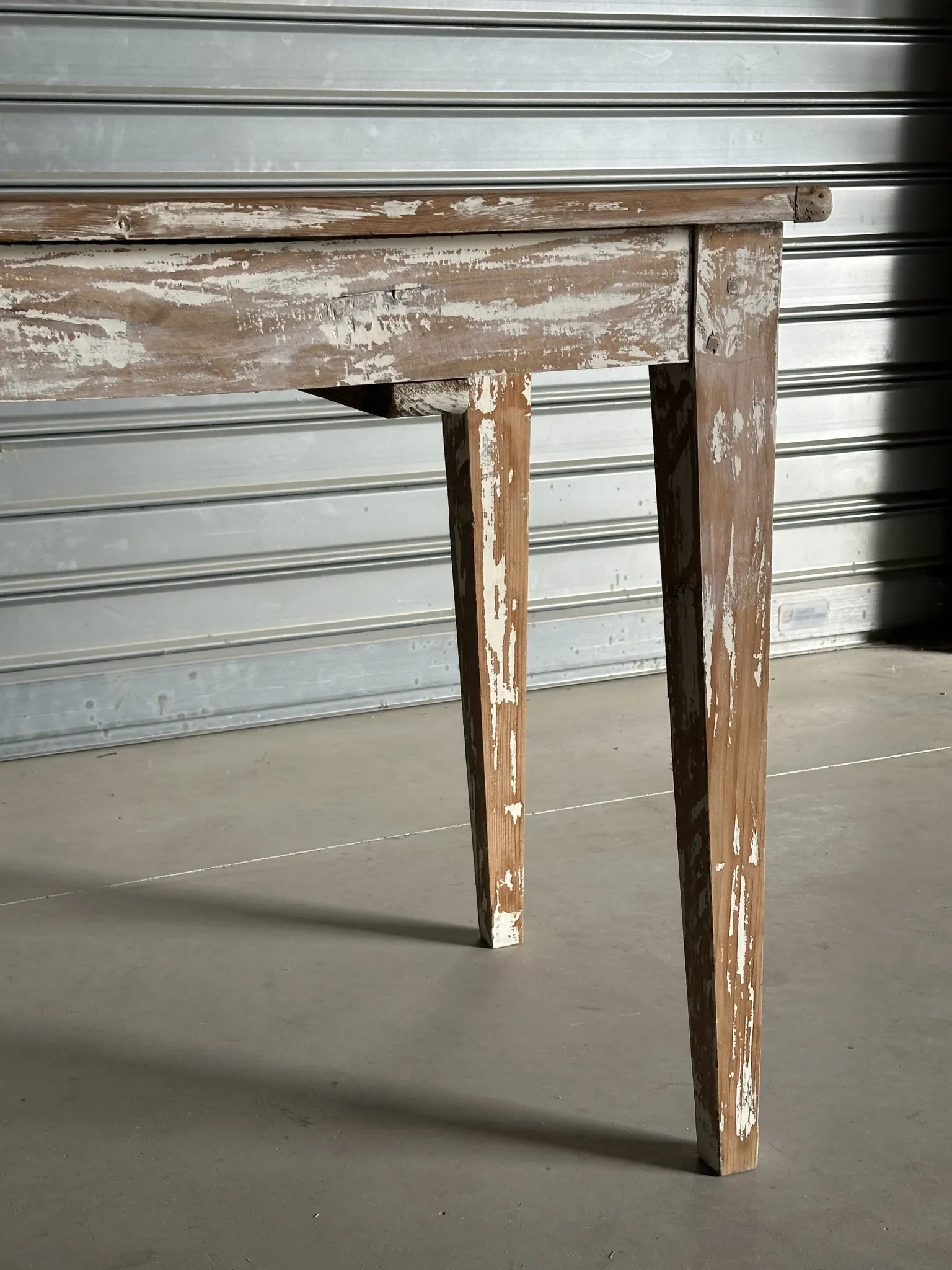 Vintage table made of raw wood with a distressed white base.