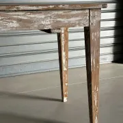 Vintage table made of raw wood with a distressed white base.