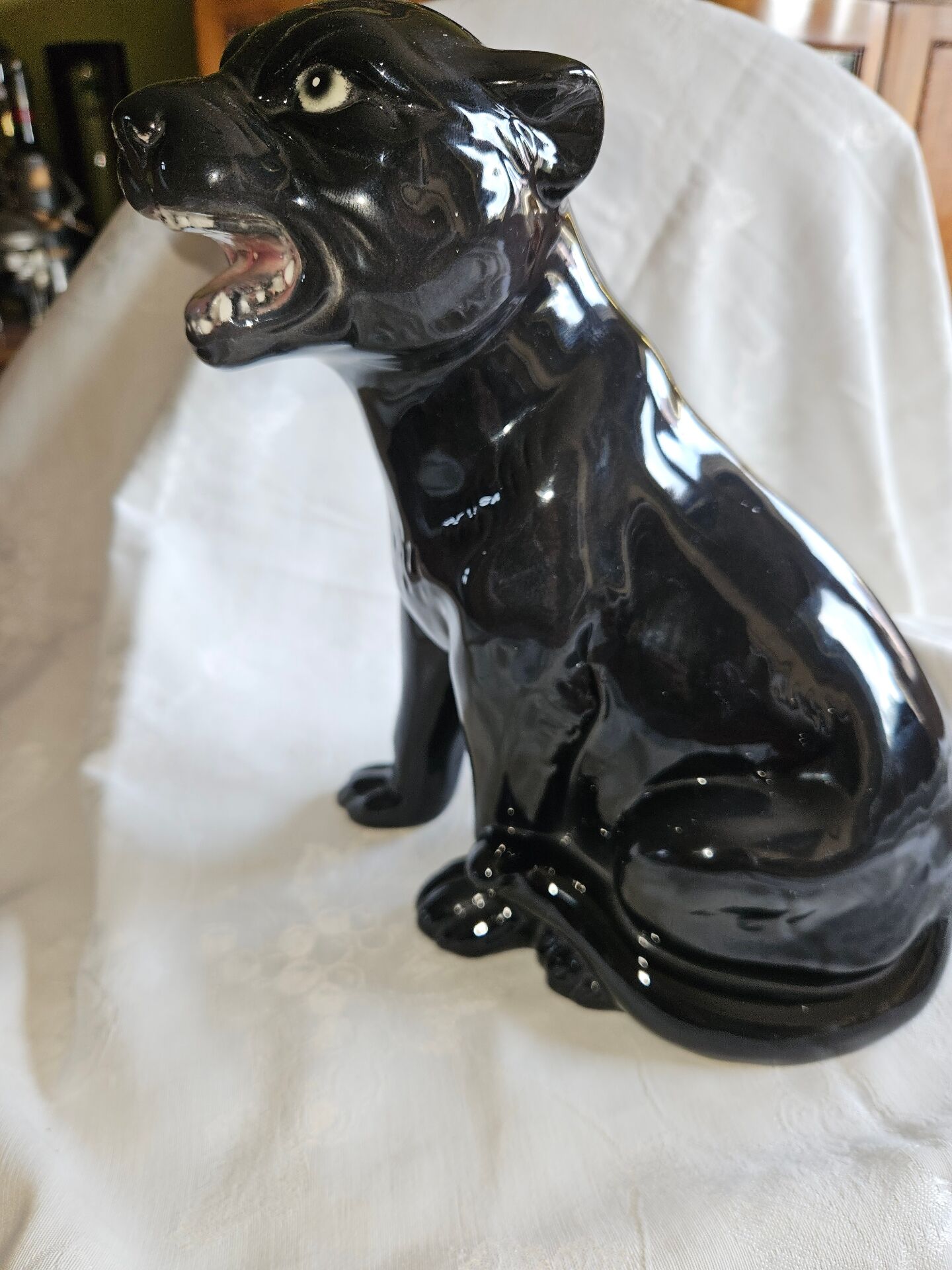Statue of a roaring panther/leopard sitting in black glazed ceramic.