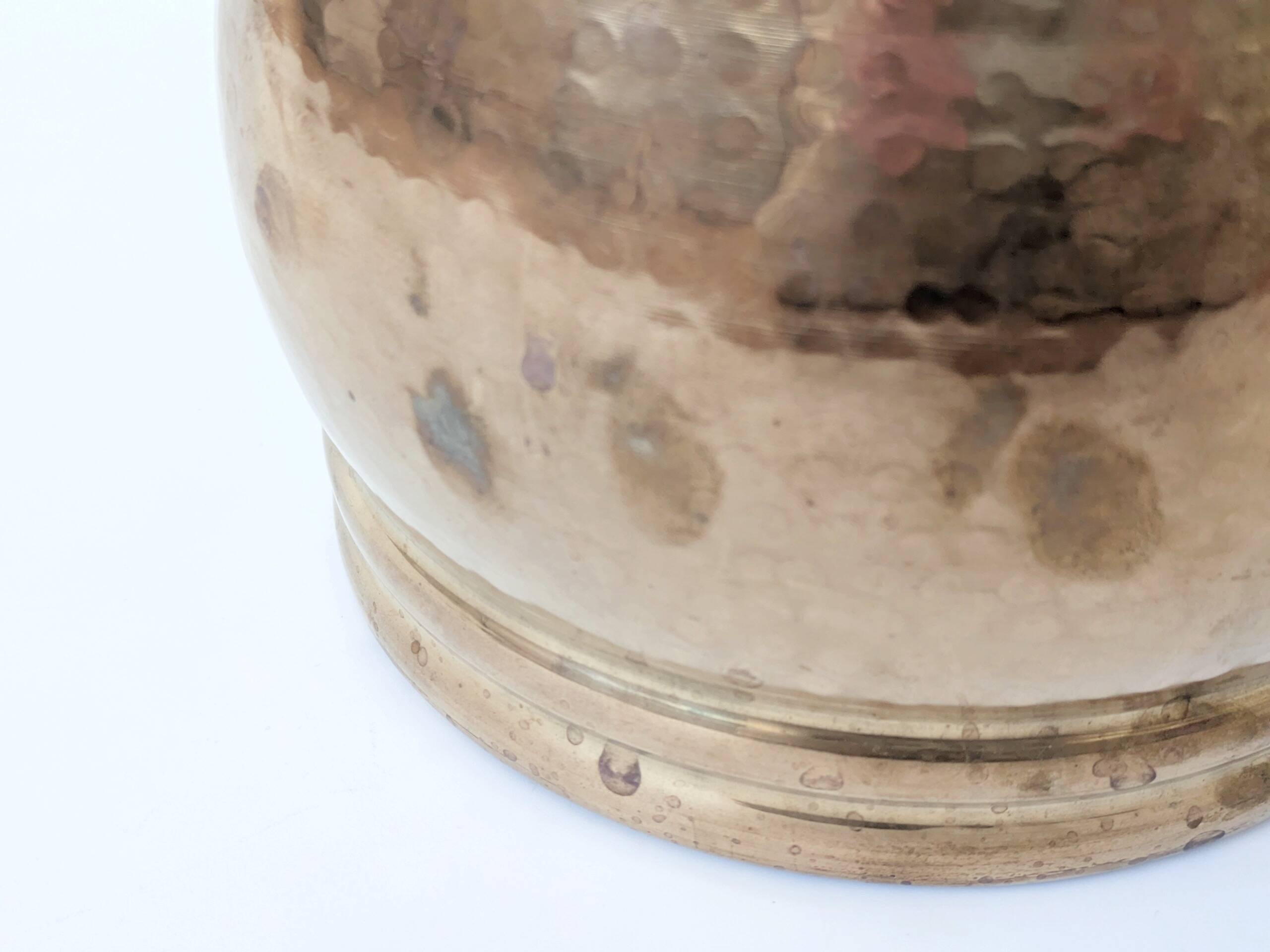 Vintage round cache-pot in hammered brass with decorative handles and patina.