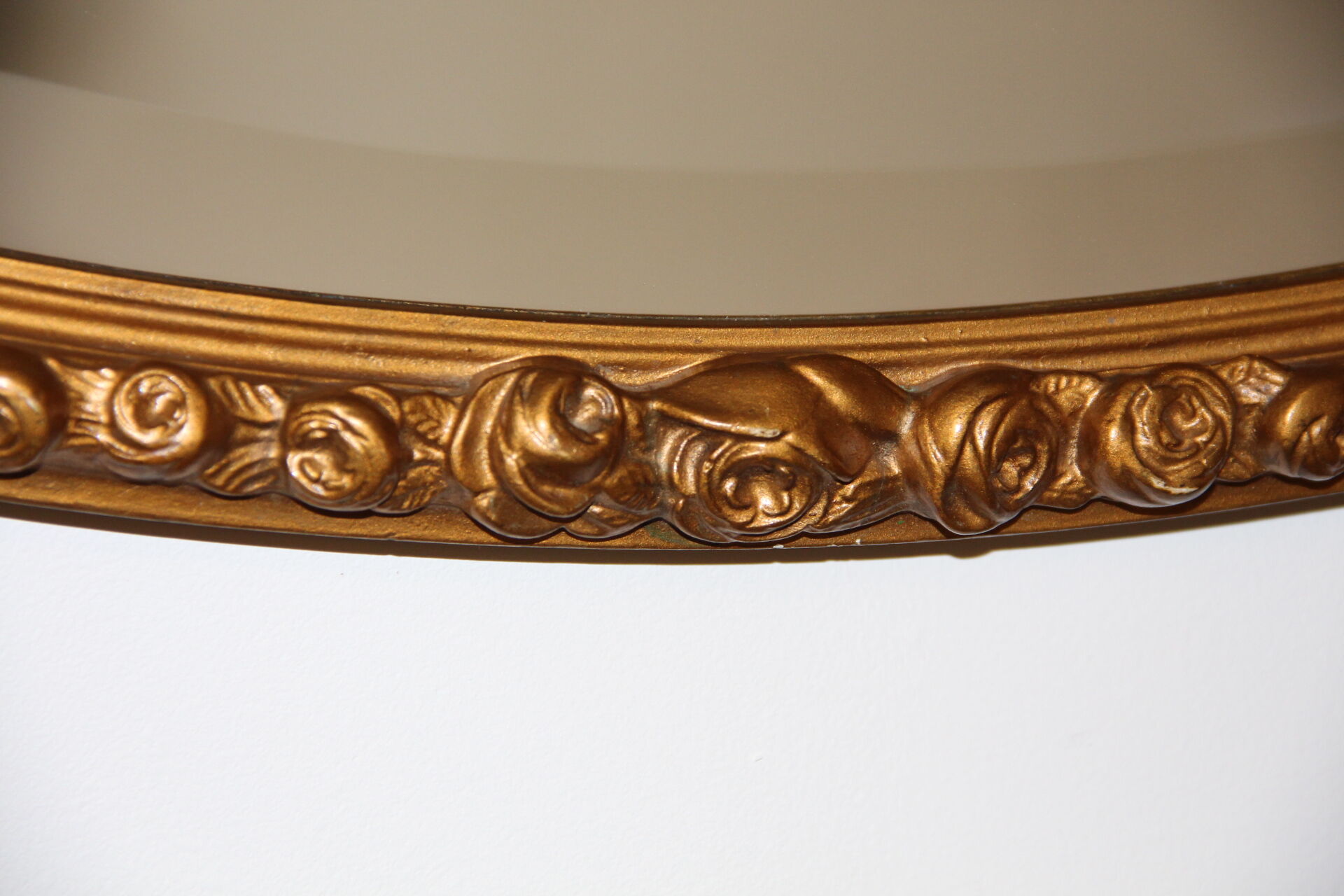 Beveled oval mirror in gilded wood