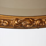 Beveled oval mirror in gilded wood