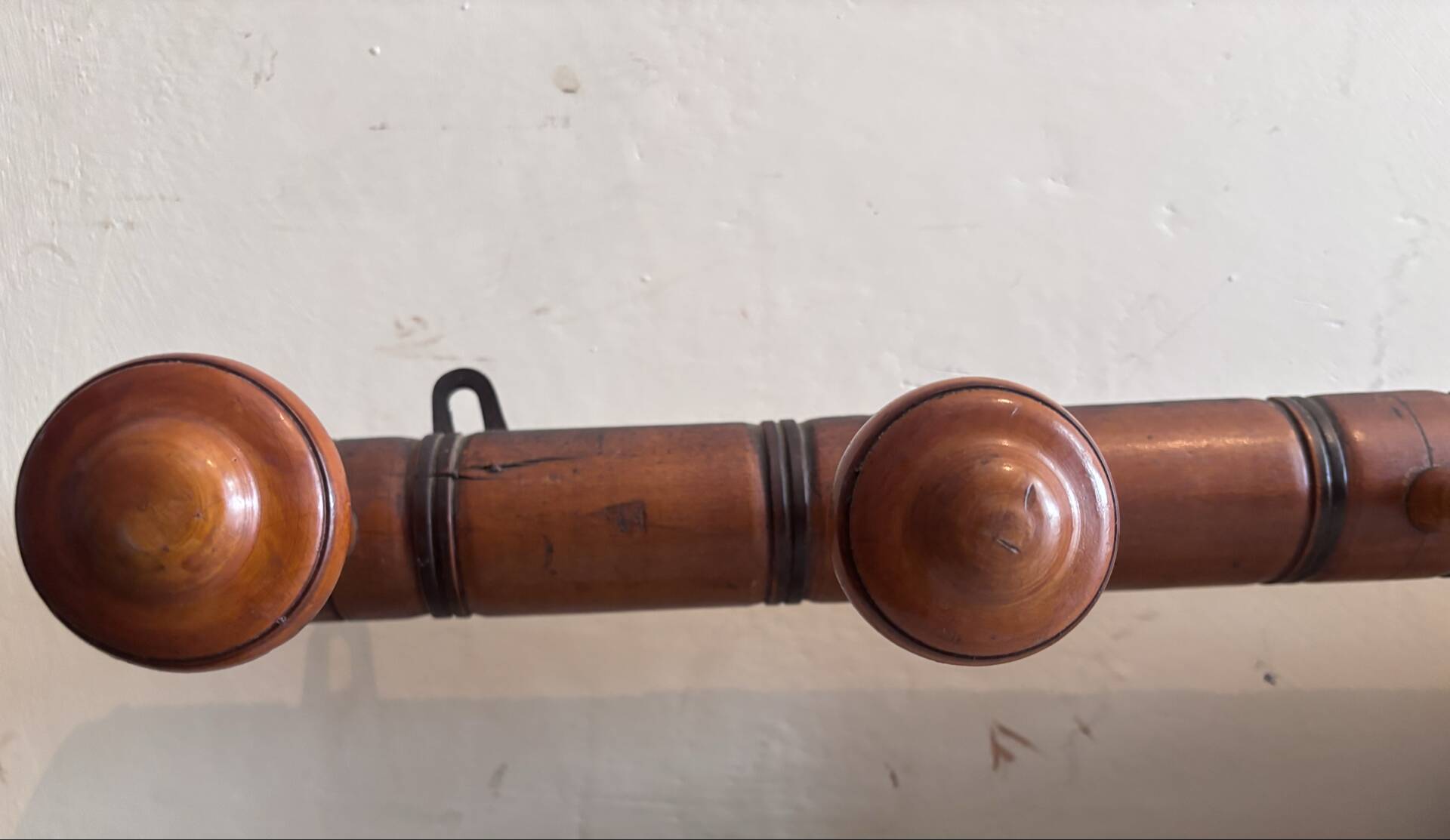 Wall-mounted coat rack with 8 turned wooden hooks in faux bamboo style.