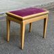 Adjustable piano stool in light beech and purple velvet.