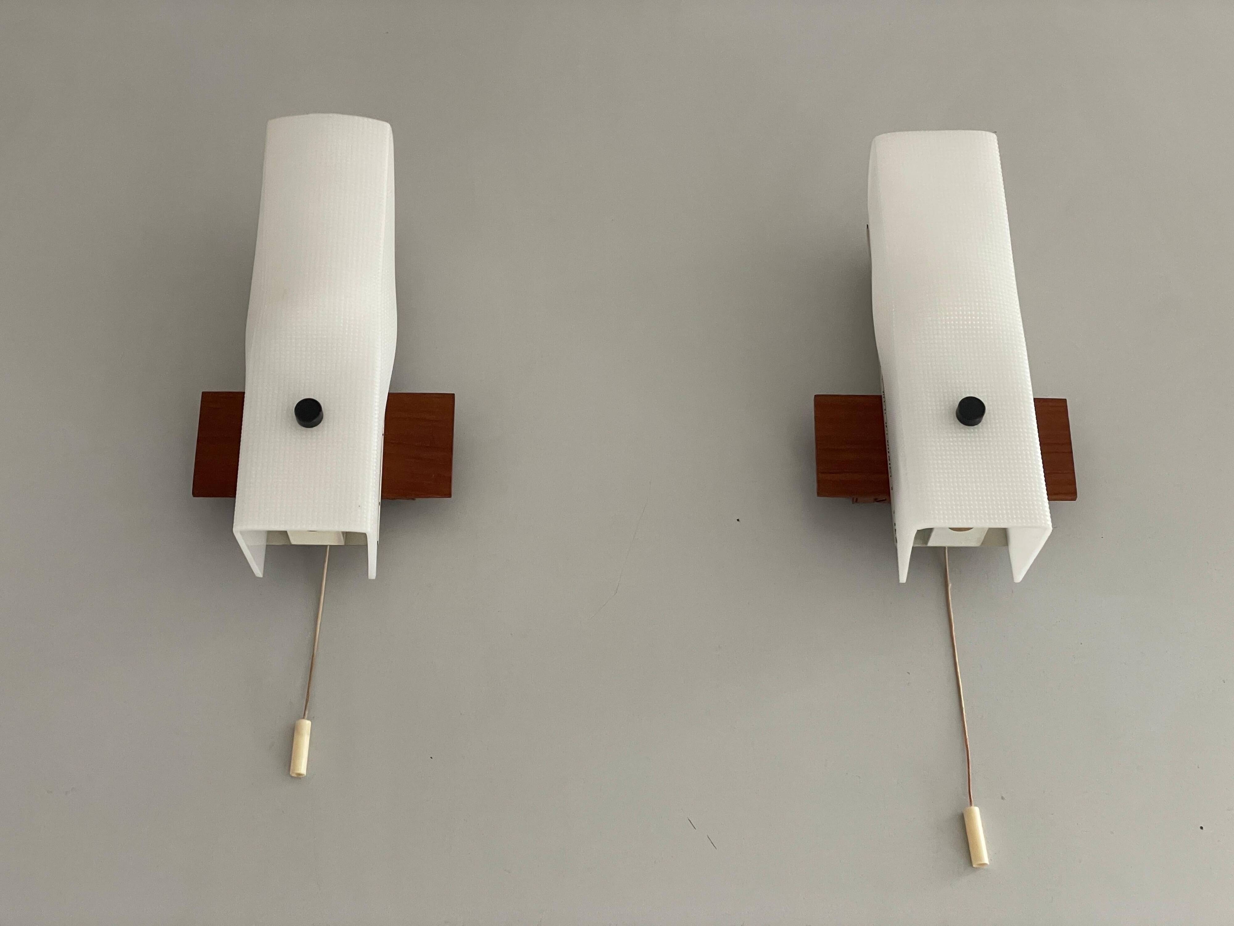 Mid-century wall lights in white plexiglass with a wooden base, 1960s, Germany.