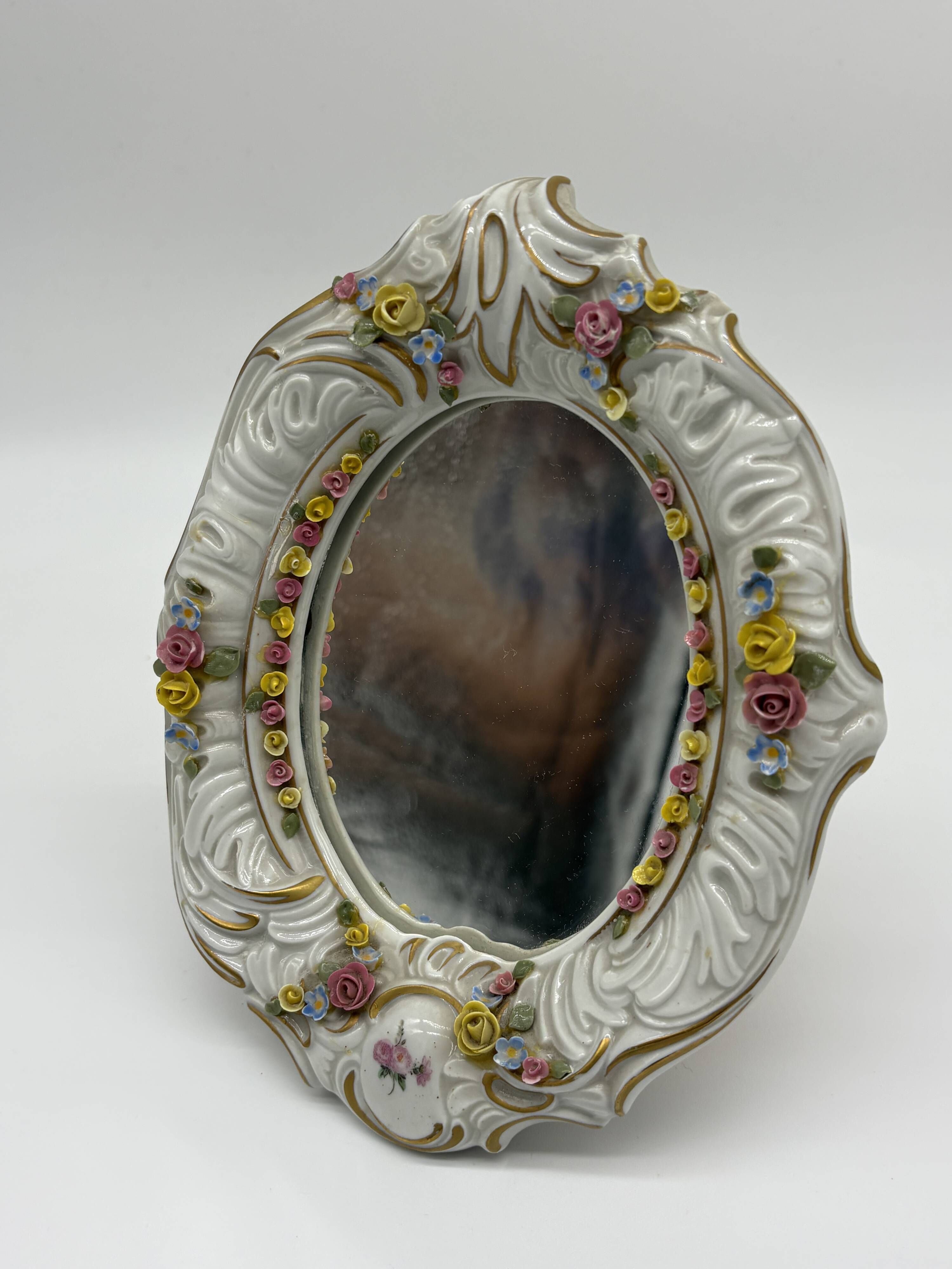 Antique porcelain mirror from Dresden with relief flowers and rococo decoration.