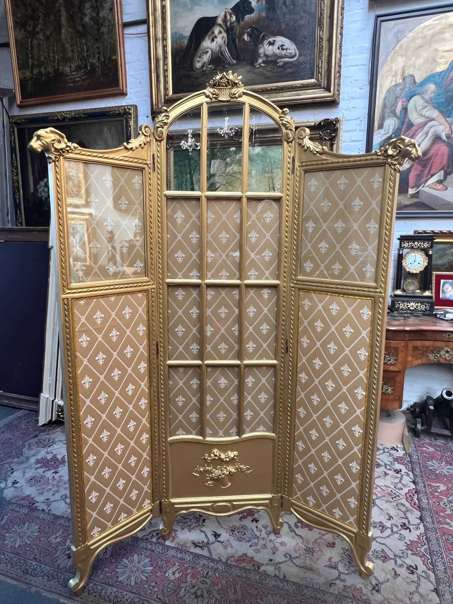 Paravent en bois doré décoré dans le style Louis XVI, orné de têtes de bélier.