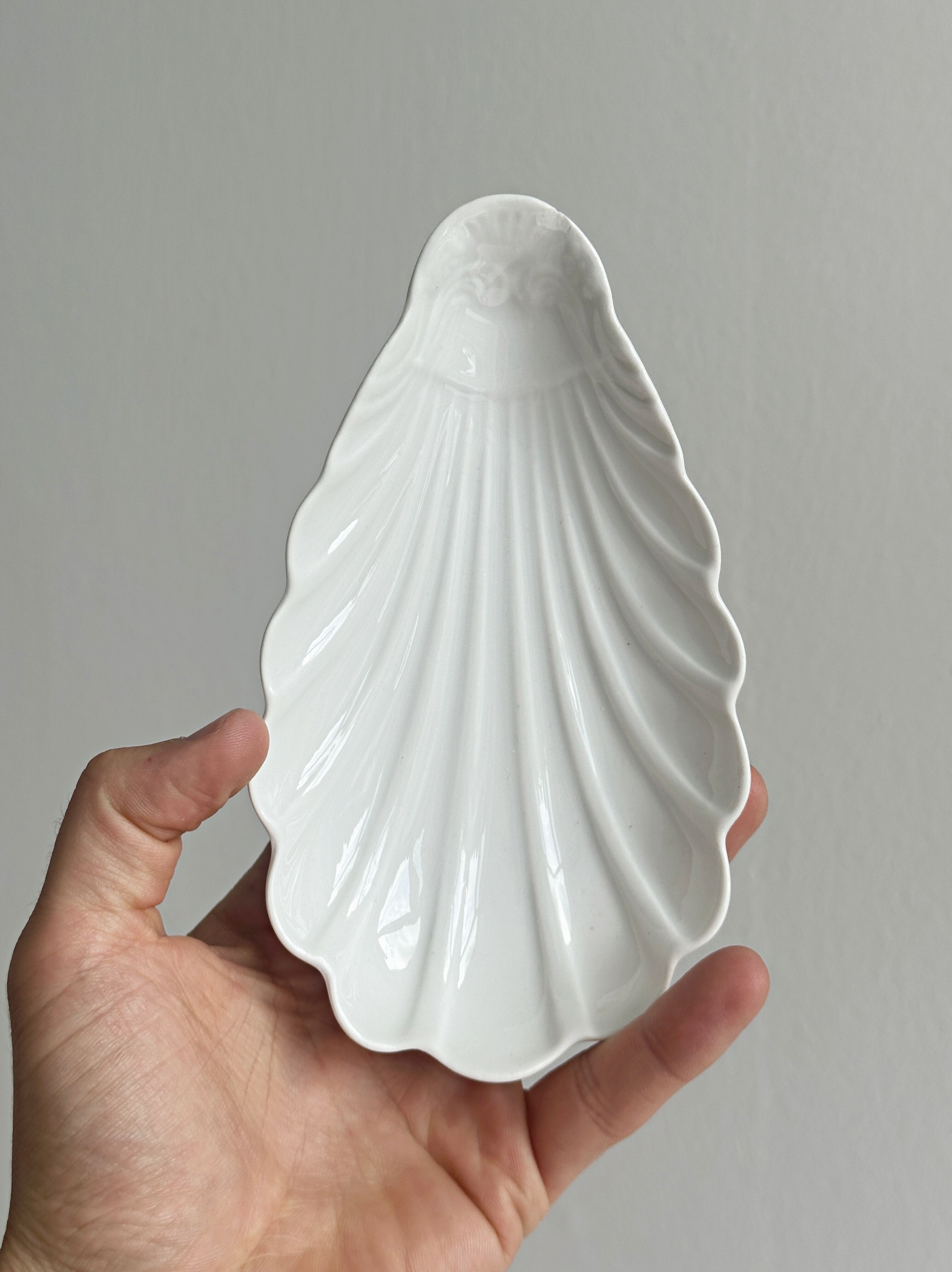 Set of white porcelain ramekins, ribbed shell shape.