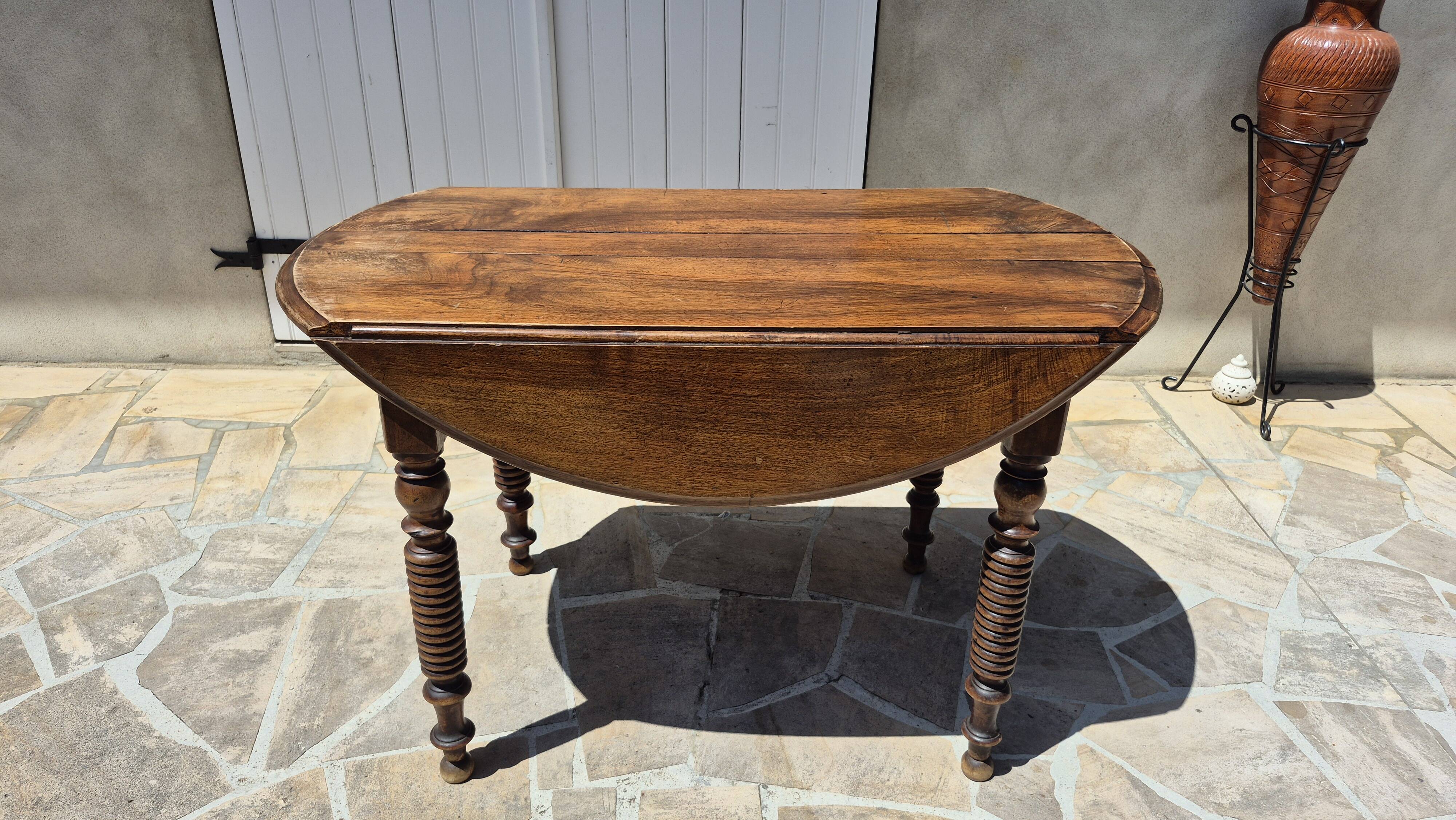 Round dining table with a drop-leaf top in solid walnut, late 19th century.