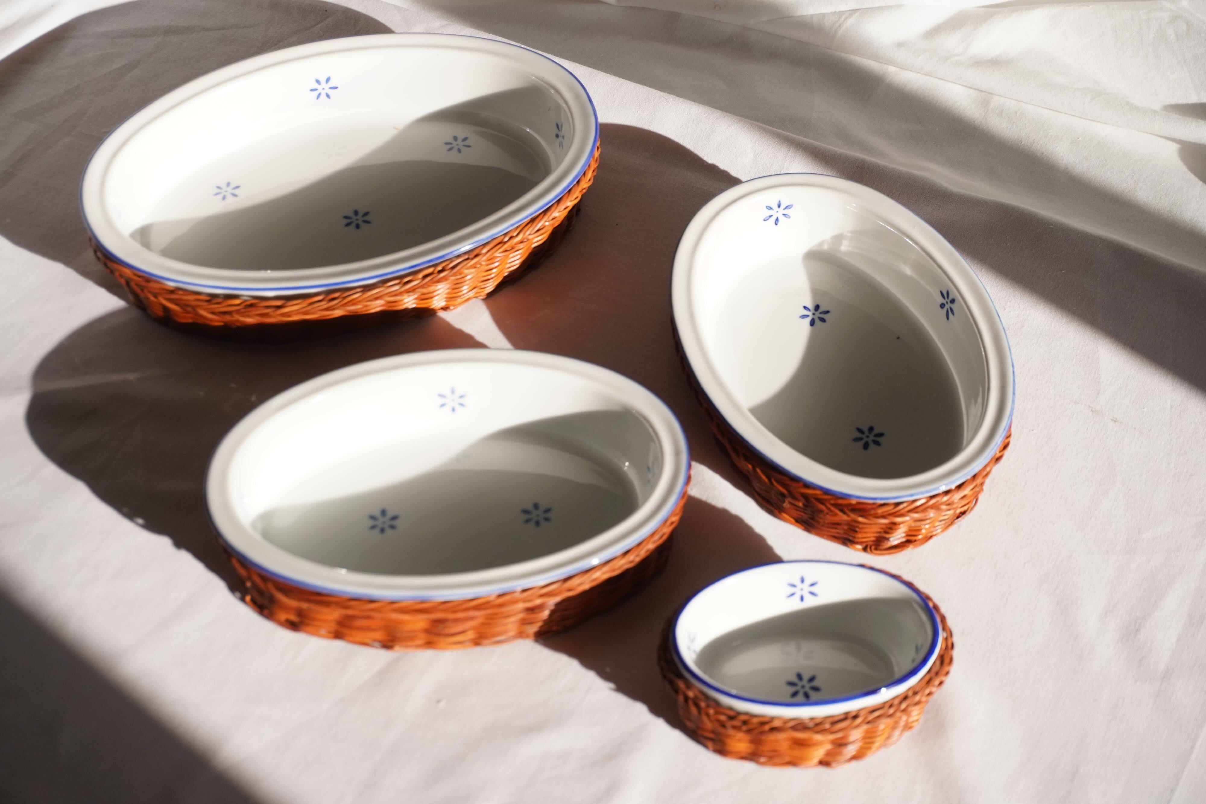 Set of 4 white porcelain dishes with blue decorations and wicker stands