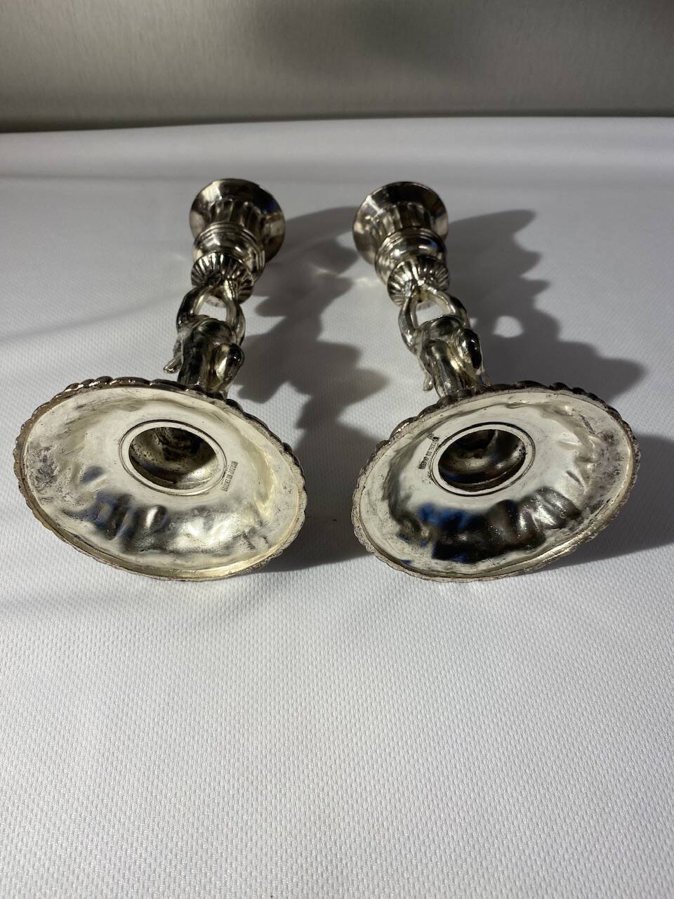 Two silver-plated metal candlesticks decorated with cherubs, 20th century