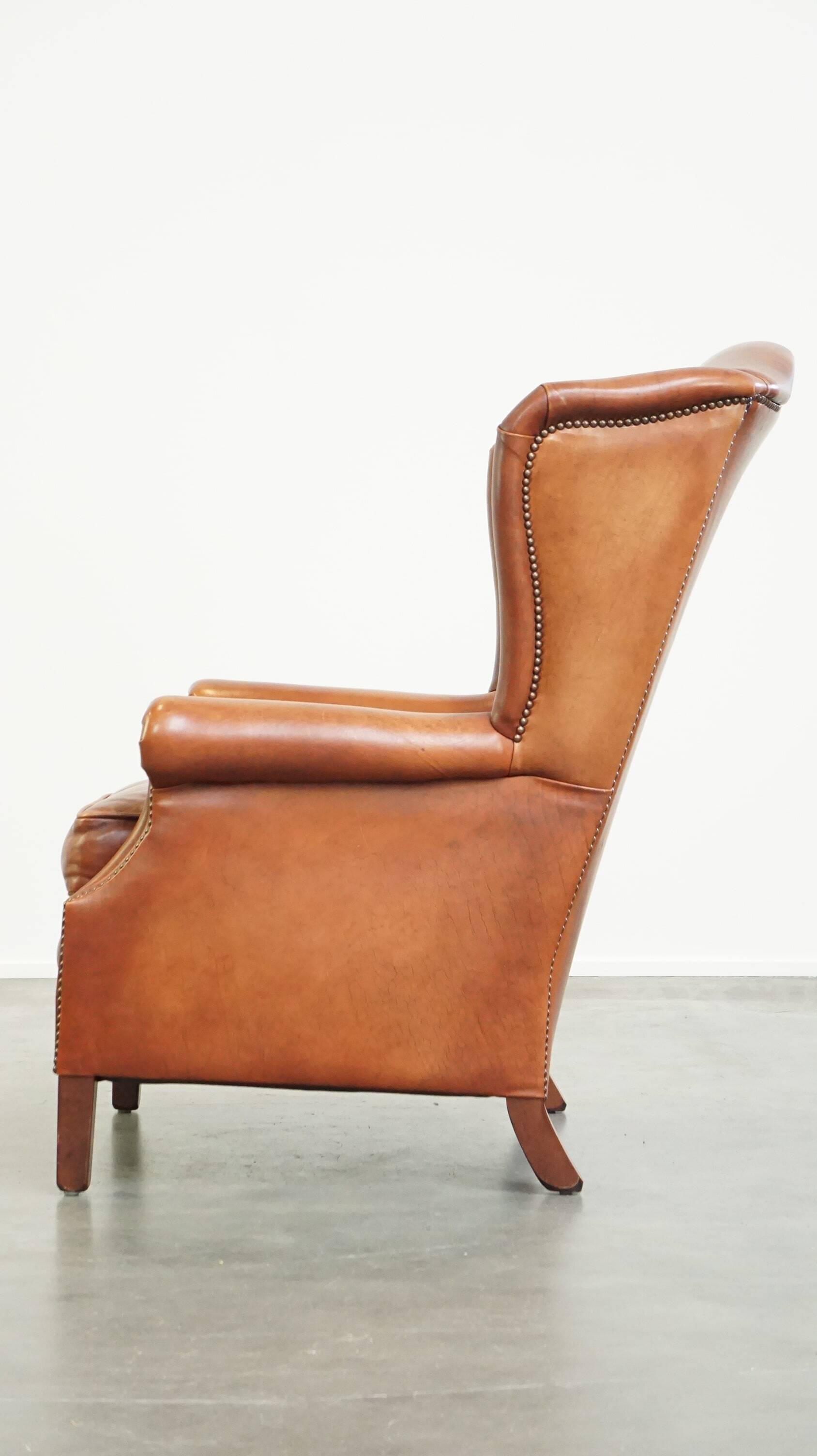 Fauteuil en cuir confortable et bien entretenu, fini avec des clous décoratifs de style anglais