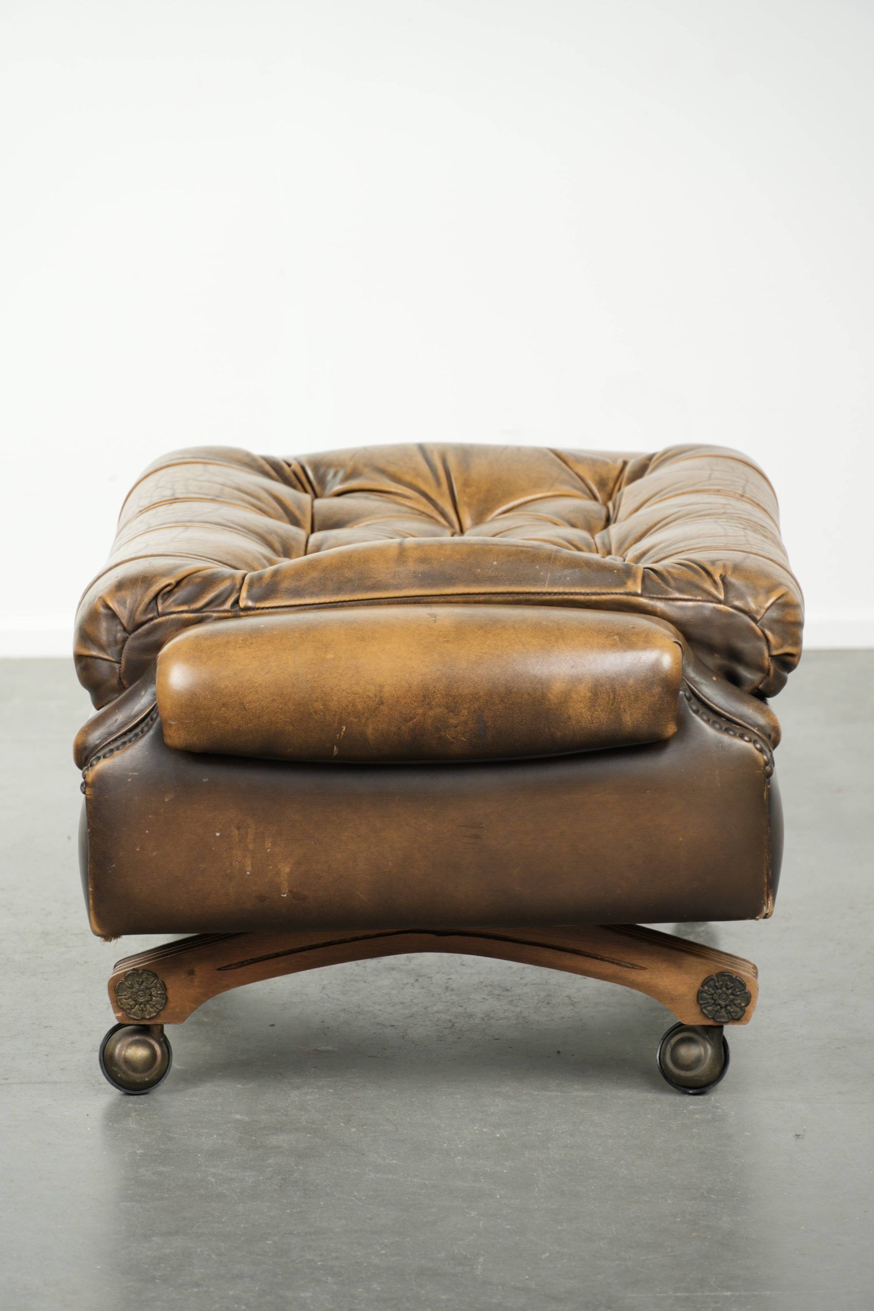 Ottoman chesterfield anglais en cuir élégant, fini avec des clous décoratifs.