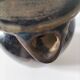 Stoneware jug with deep black drips on a sandy background.