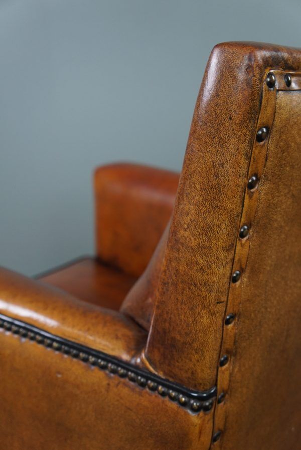 Art deco armchair in sheepskin with black piping and decorative nails