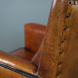 Art deco armchair in sheepskin with black piping and decorative nails