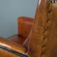 Art deco armchair in sheepskin with black piping and decorative nails