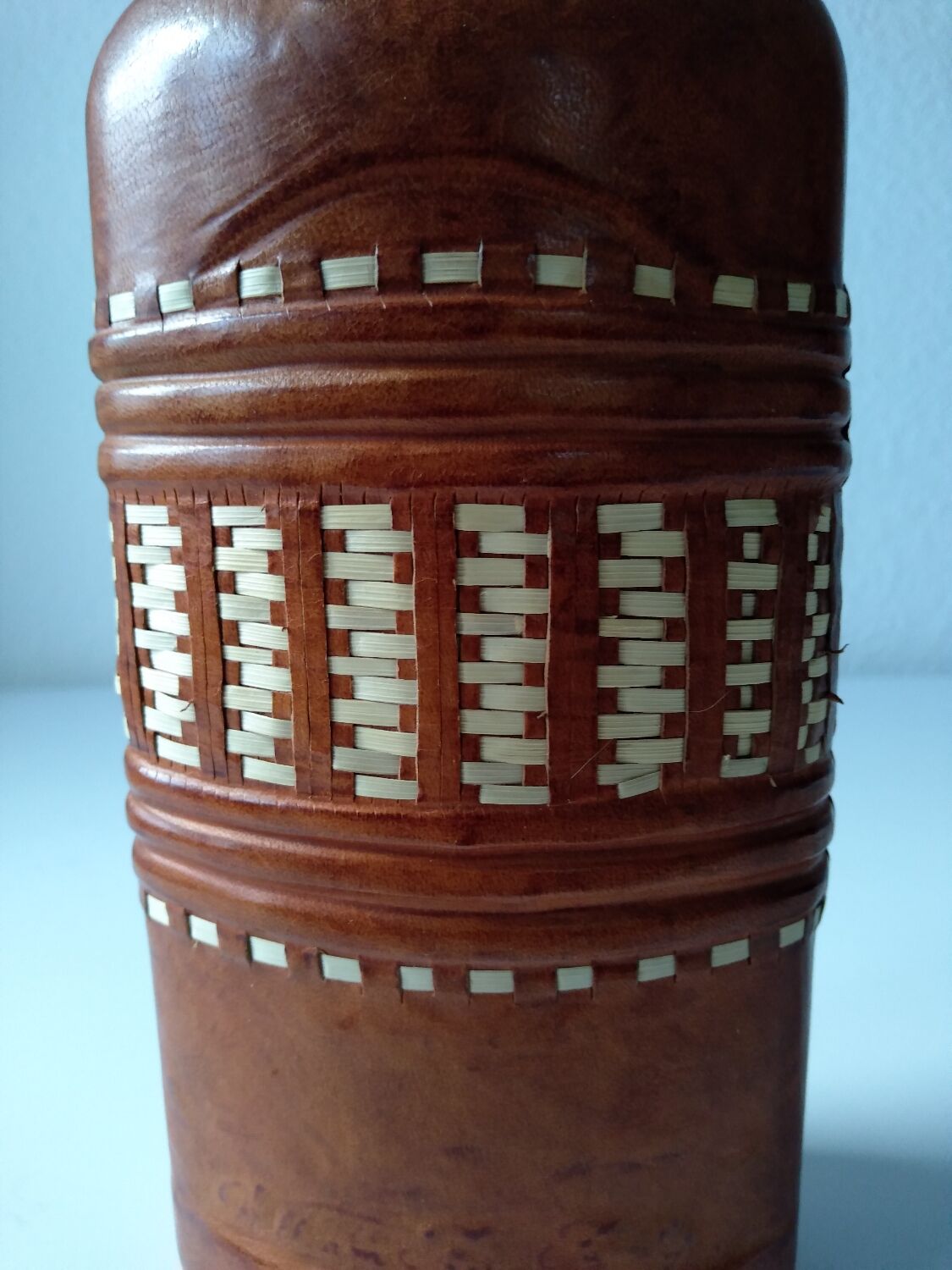 Vintage glass bottle covered with light brown leather and wicker