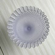 Purple glass pedestal bowl with wavy border and relief pattern.