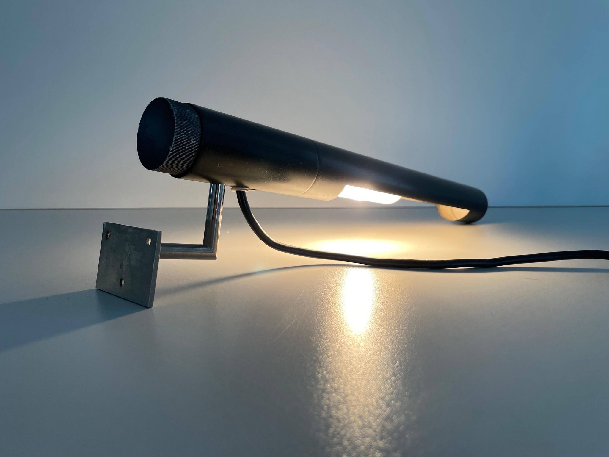 Minimalist black metal wall light with a cylindrical design, 1960s, Germany.