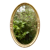 Old large oval wall mirror in golden resin